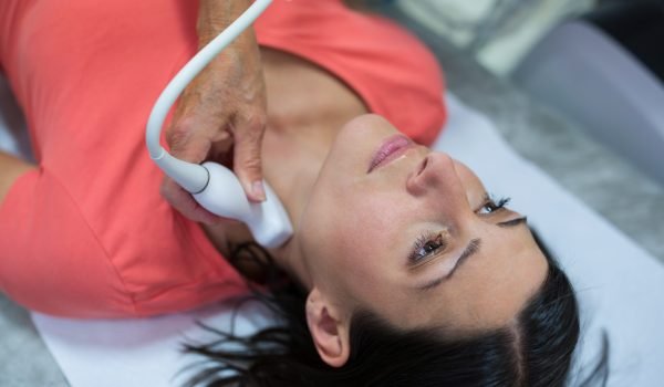 Woman getting ultrasound of a thyroid from doctor in hospital